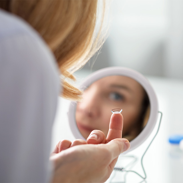 woman with contact in mirror